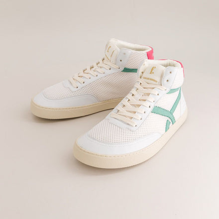 White mid-ankle barefoot sneakers with a green accent on a beige background