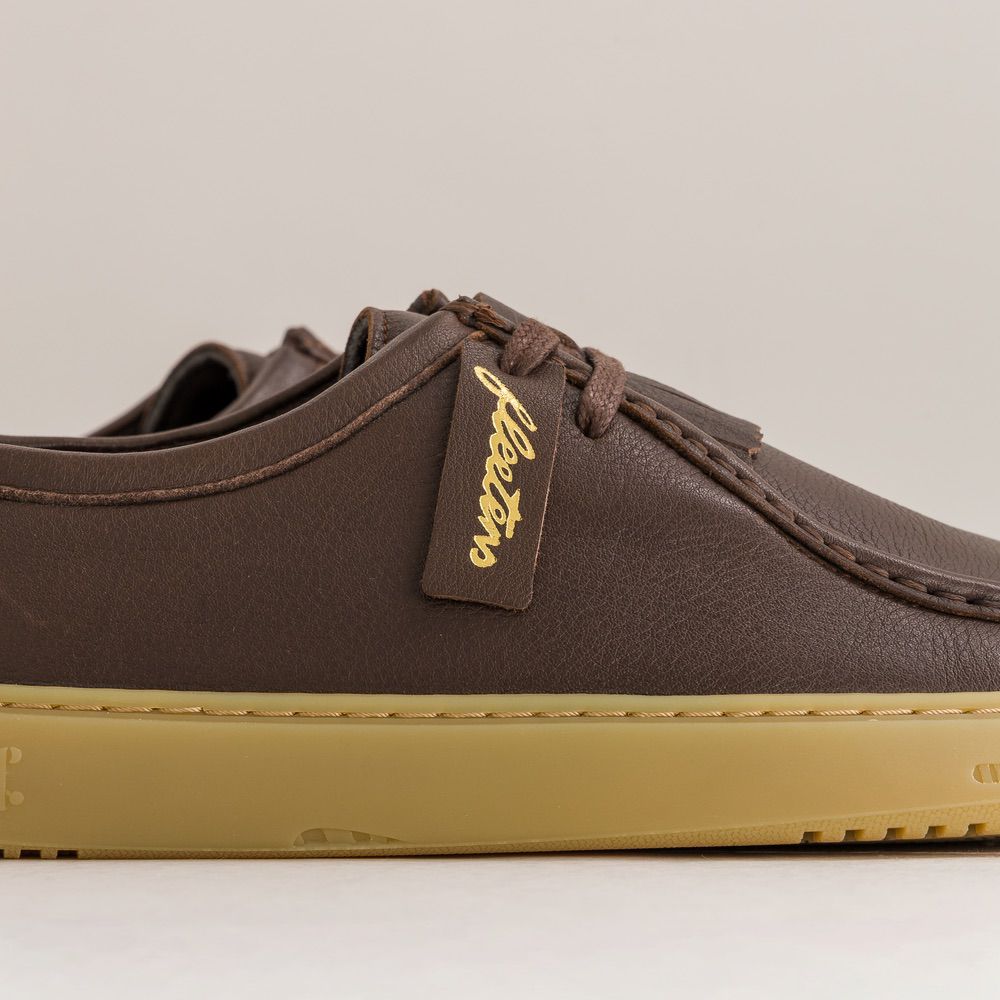Brown barefoot derbies with a visible brand tag on a neutral background