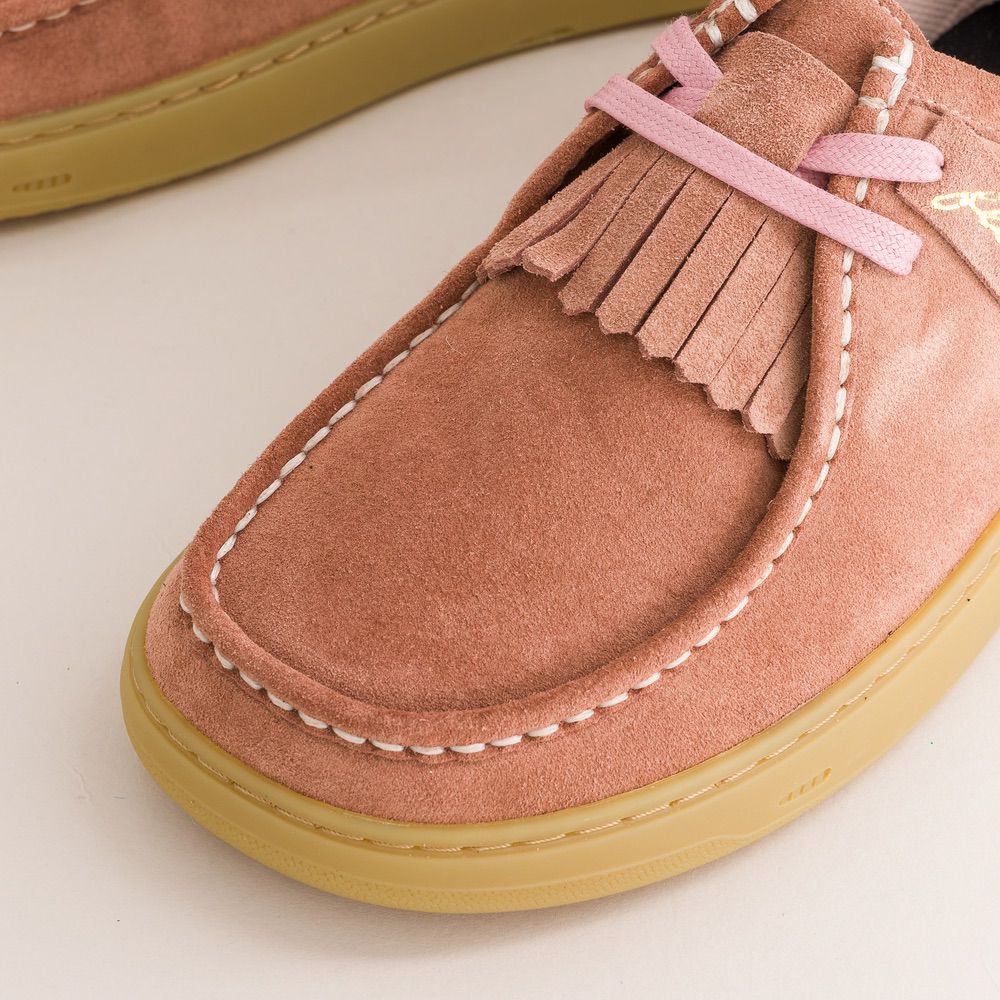 Pink suede barefoot derbies with fringes and yellow sole on a light background