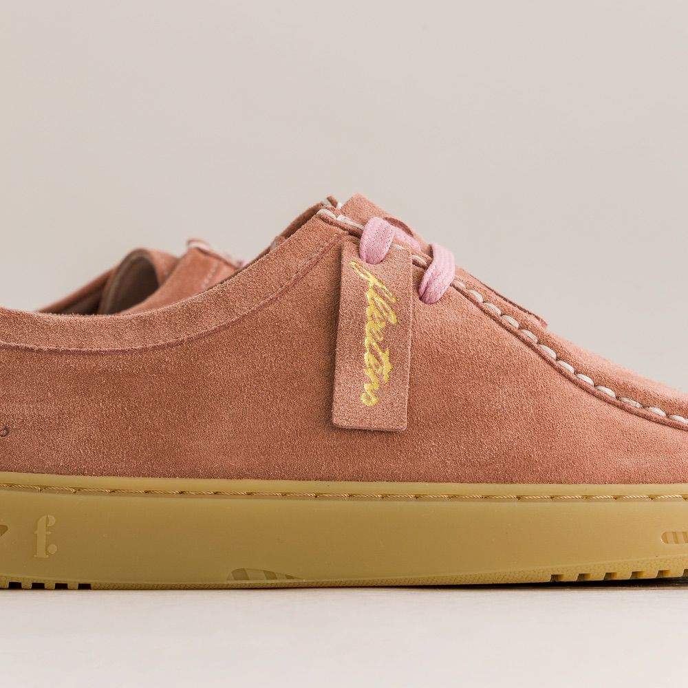 Rose suede barefoot derbies with a yellow tag on a beige background