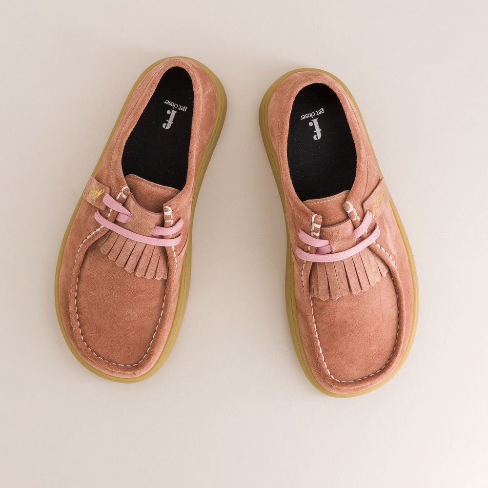 Pair of rose barefoot derbies with pink laces on a beige background