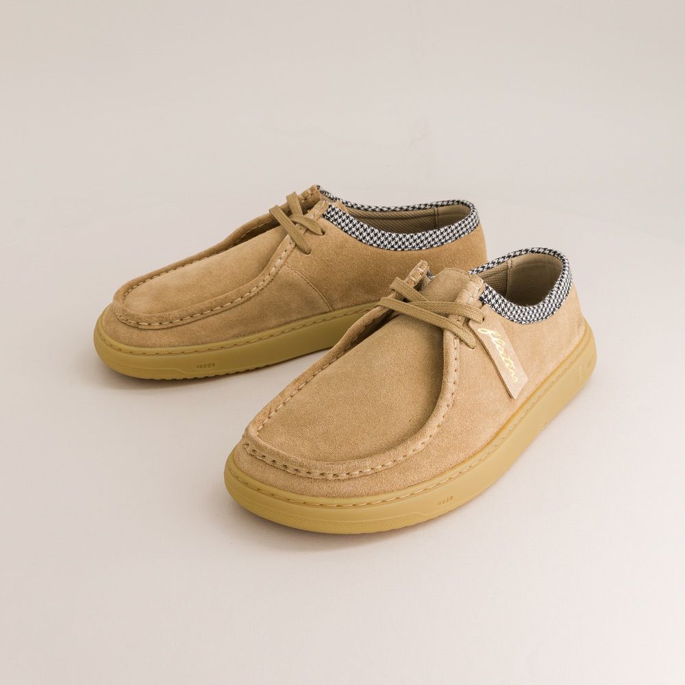 Pair of tan children's shoes with checkered lining on a light beige background