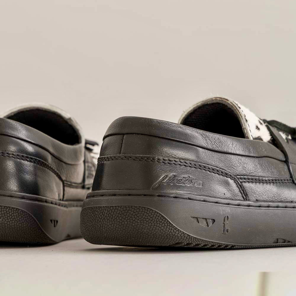 Black leather shoes with brand logo on a light gray background