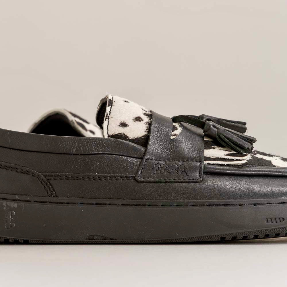 Black loafer with cow print insole on a light gray background
