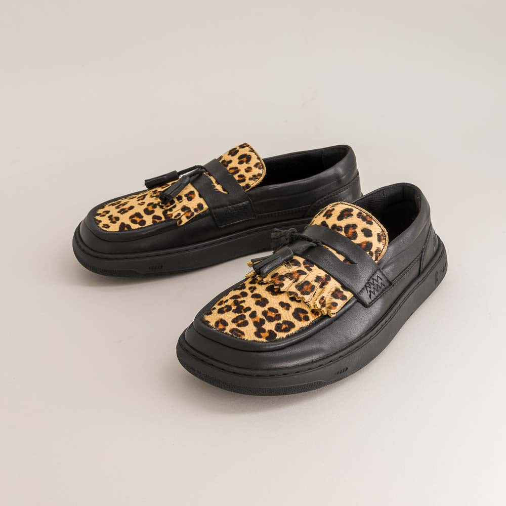 Pair of black barefoot loafers with leopard print straps on a light gray background
