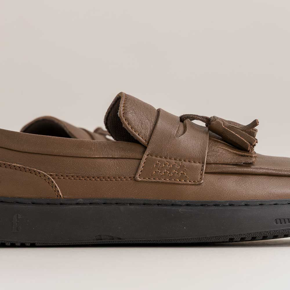 Brown barefoot loafer shoe with a strap on a light gray background
