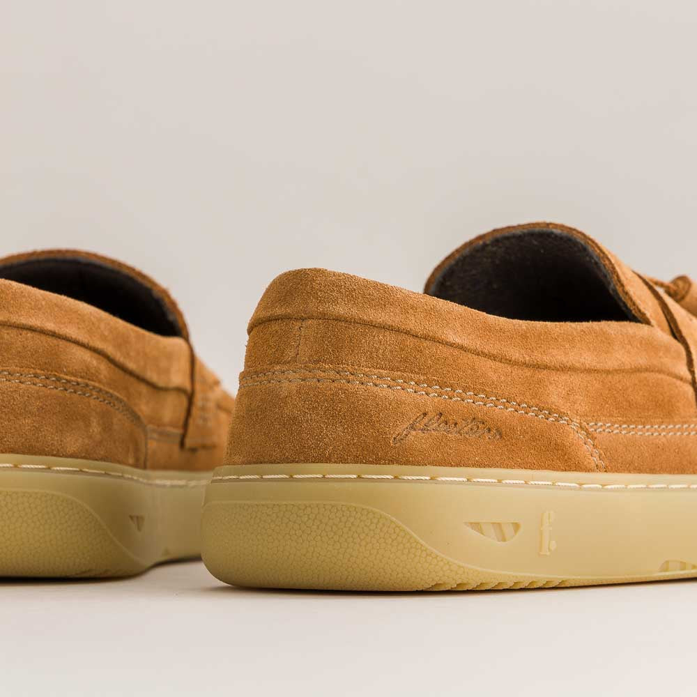 Pair of brown suede shoes with beige soles on a light background