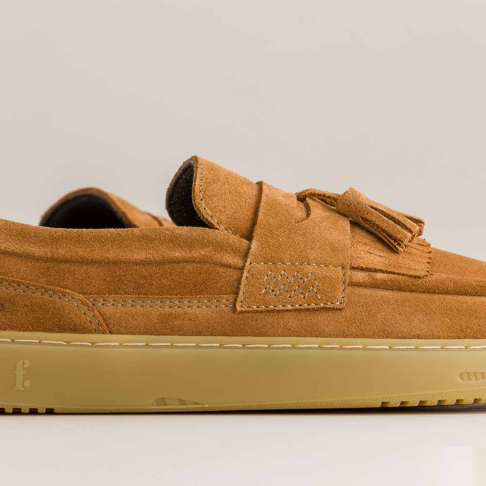 Brown suede shoe with a tassel on a light gray background