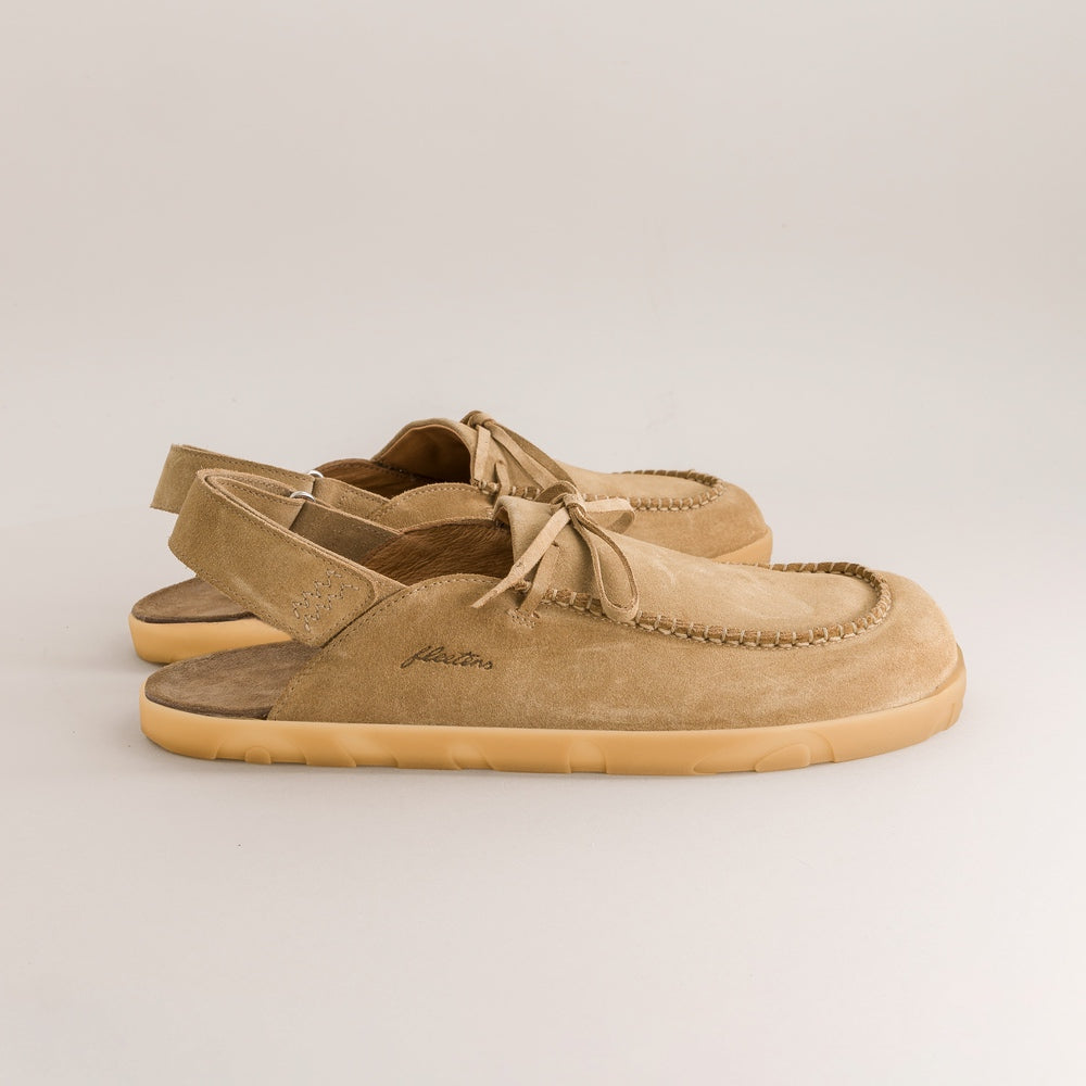 Pair of tan suede barefoot mules with a brand logo on a light gray background