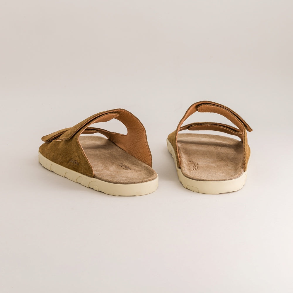 Pair of brown barefoot sandals on a light beige background