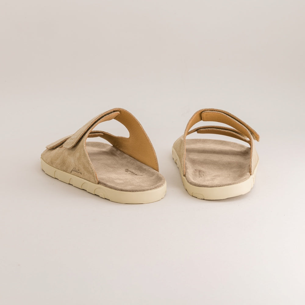 Pair of beige suede barefoot sandals on a light gray background