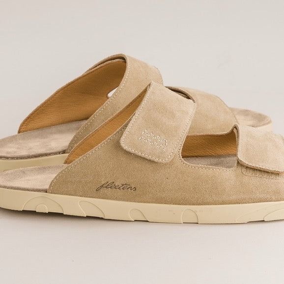 Beige barefoot sandals with a brand logo on a light gray background