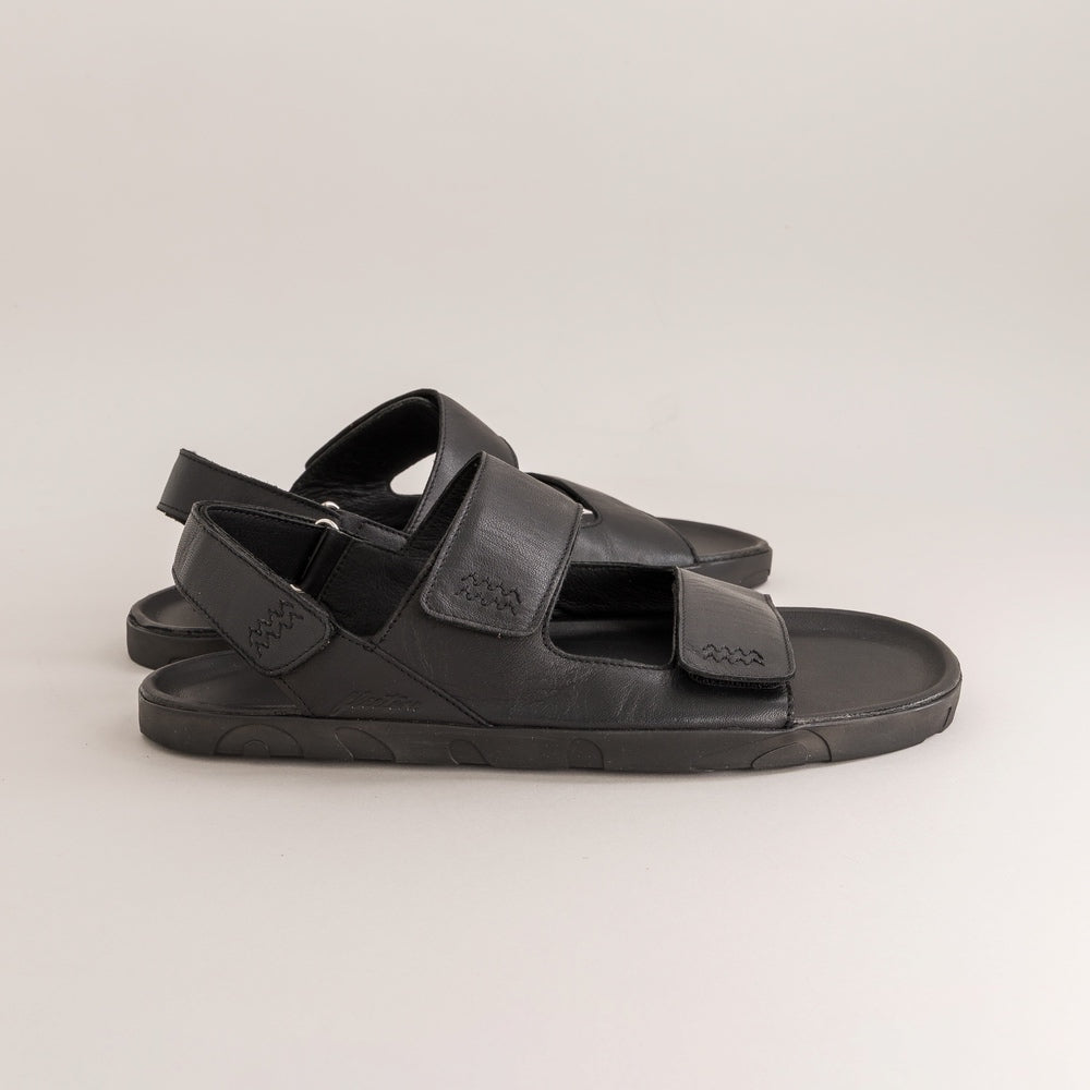 Black barefoot sandals with multiple straps on a light gray background