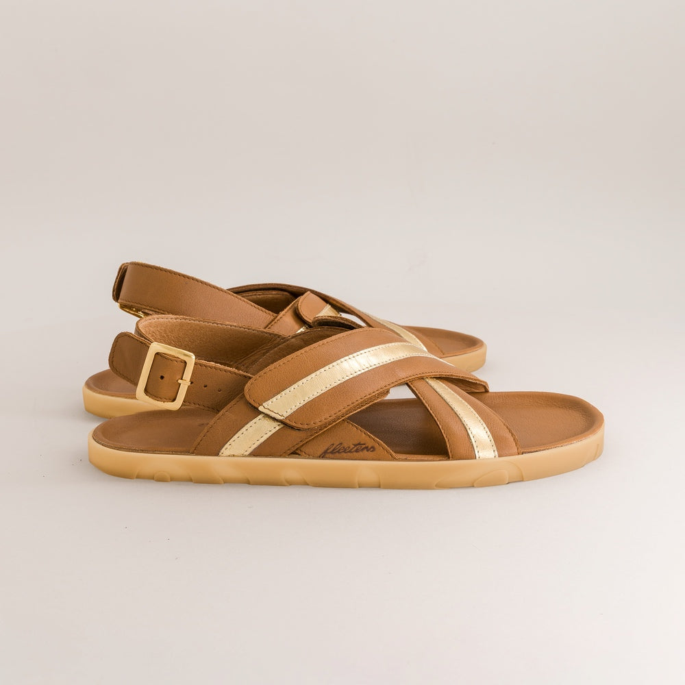 Pair of tan barefoot sandals with gold accents on a light beige background
