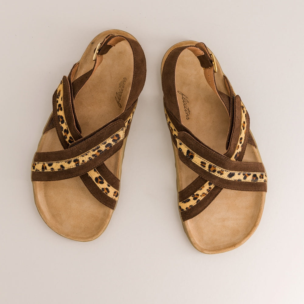 Pair of brown barefoot sandals with leopard print straps on a light gray background