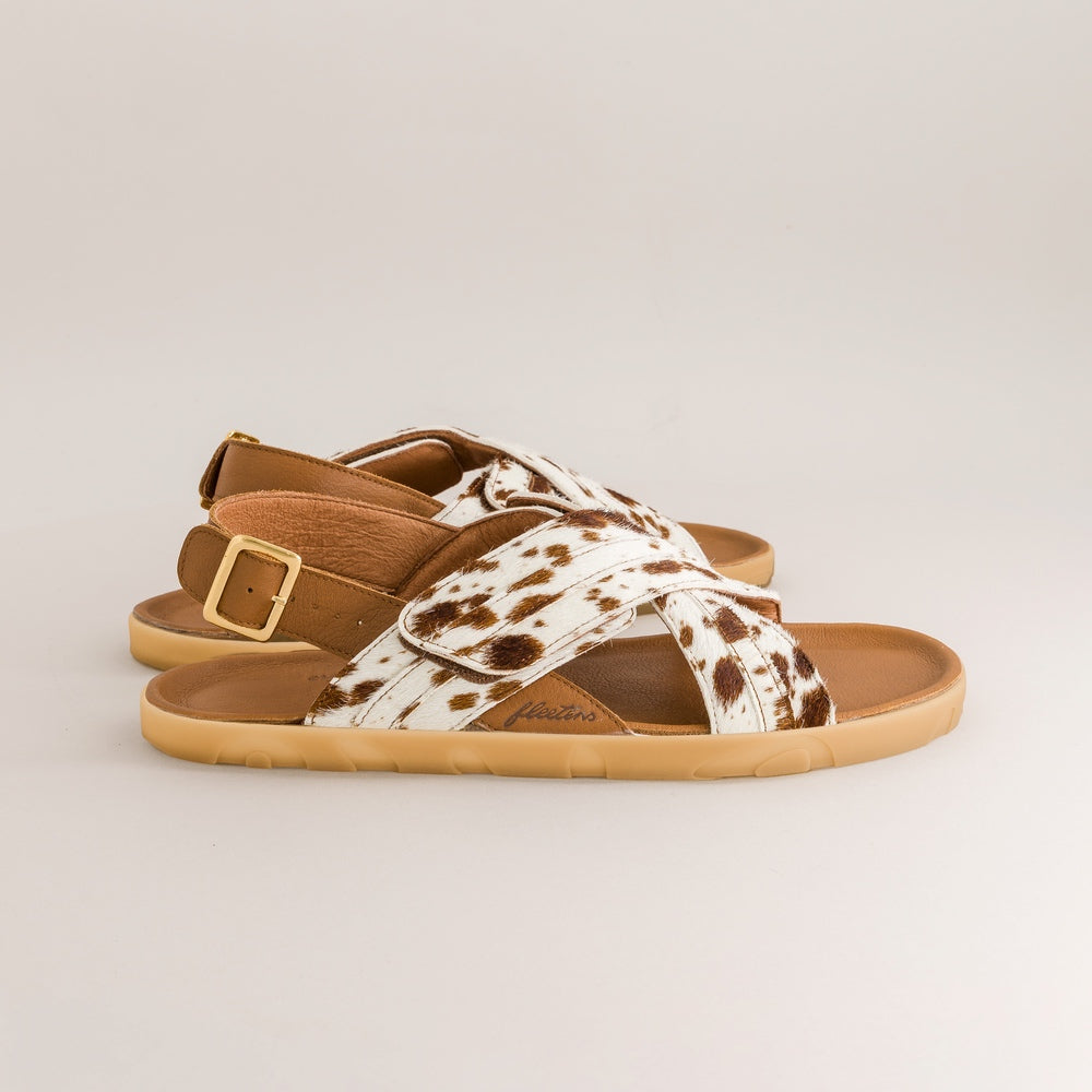 Pair of barefoot sandals with cow print straps on a light gray background
