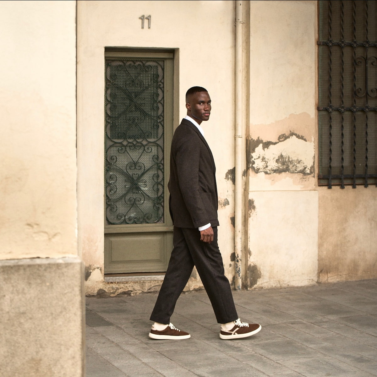 Man in a suit walking with brown barefoot sneakers 