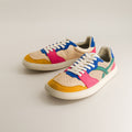Colorful sneakers with a beige, blue, pink, and yellow design on a light gray background