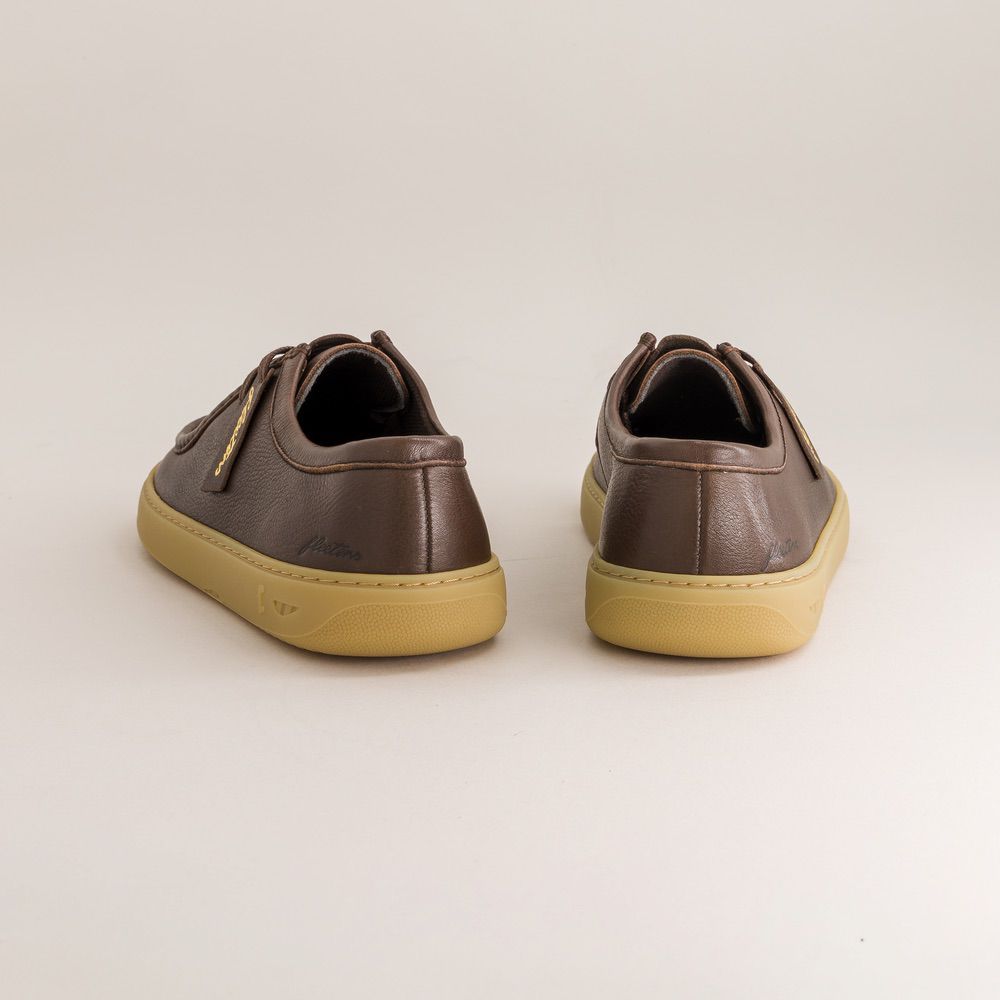Pair of brown barefoot derbies with yellow soles on a light beige background