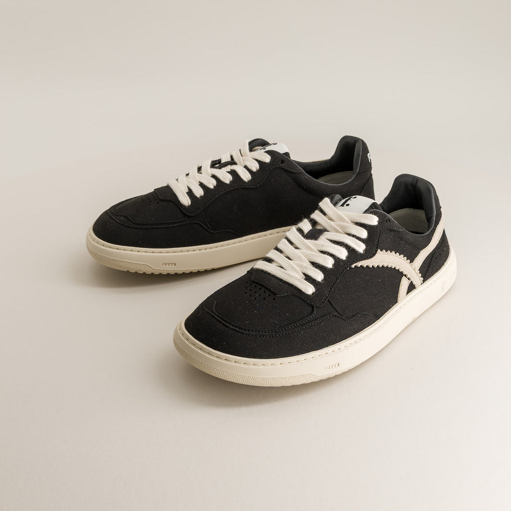 Pair of black barefoot sneakers with white laces on a light gray background