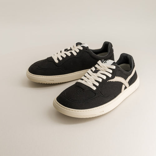 Pair of black barefoot sneakers with white laces on a light gray background