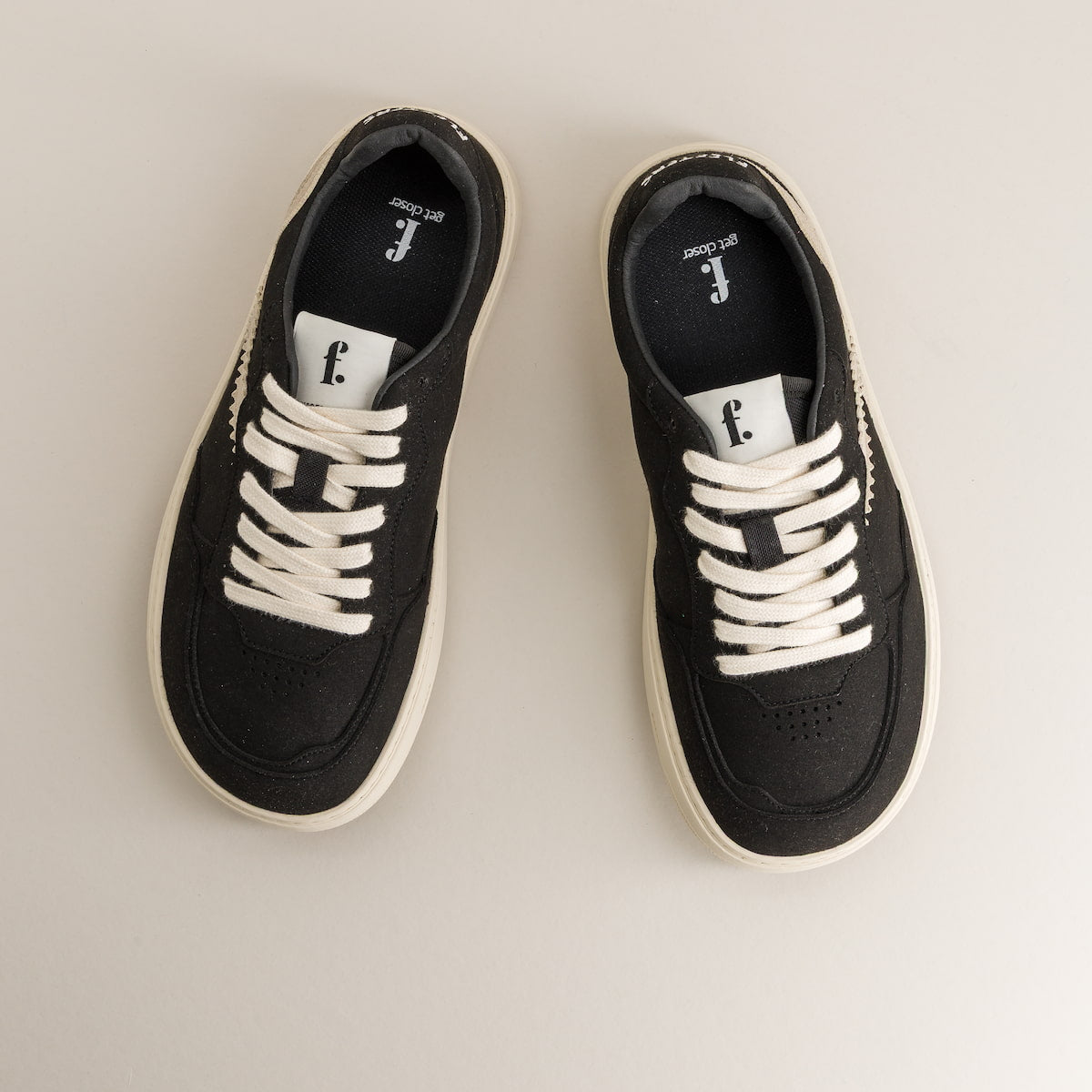 Pair of black barefoot sneakers with white laces on a light gray background