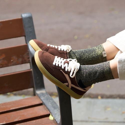 Person wearing brown and pink barefoot sneakers with white laces 