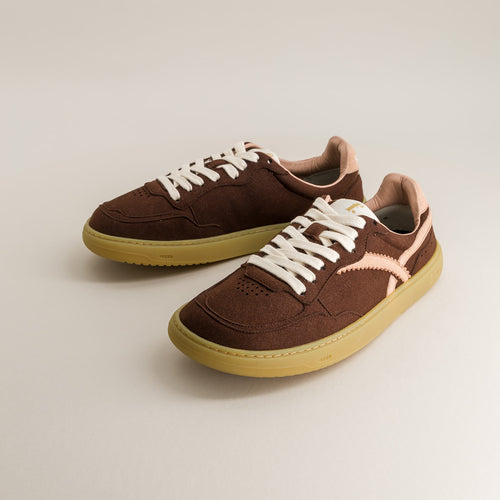 Brown barefoot sneakers with white laces on a light gray background