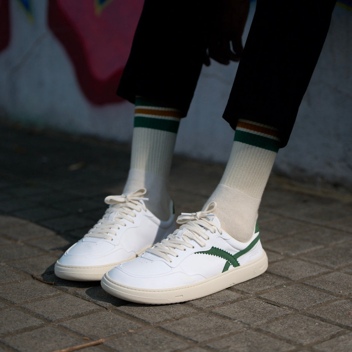 person wearing white and green barefoot sneakers 