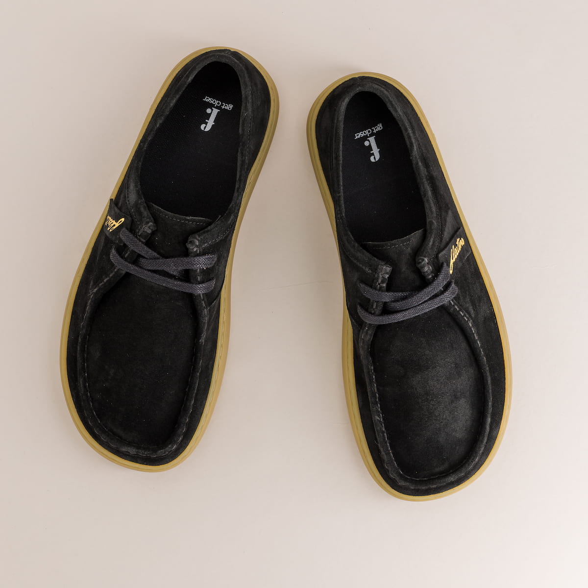Pair of black shoes with gold accents on a light beige background