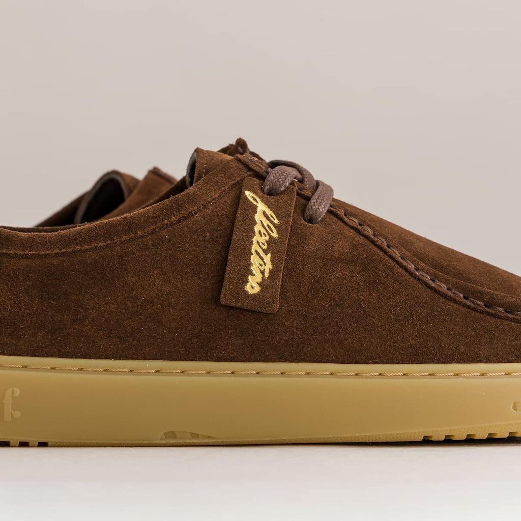 Brown suede derby shoe with tan sole on a light gray background