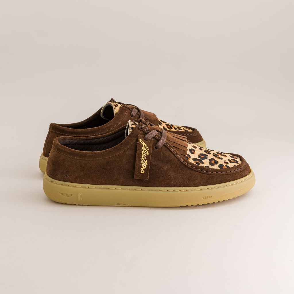 Brown suede shoes with leopard print accents on a beige background