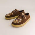 Pair of brown barefoot derbies with leopard print soles on a light beige background