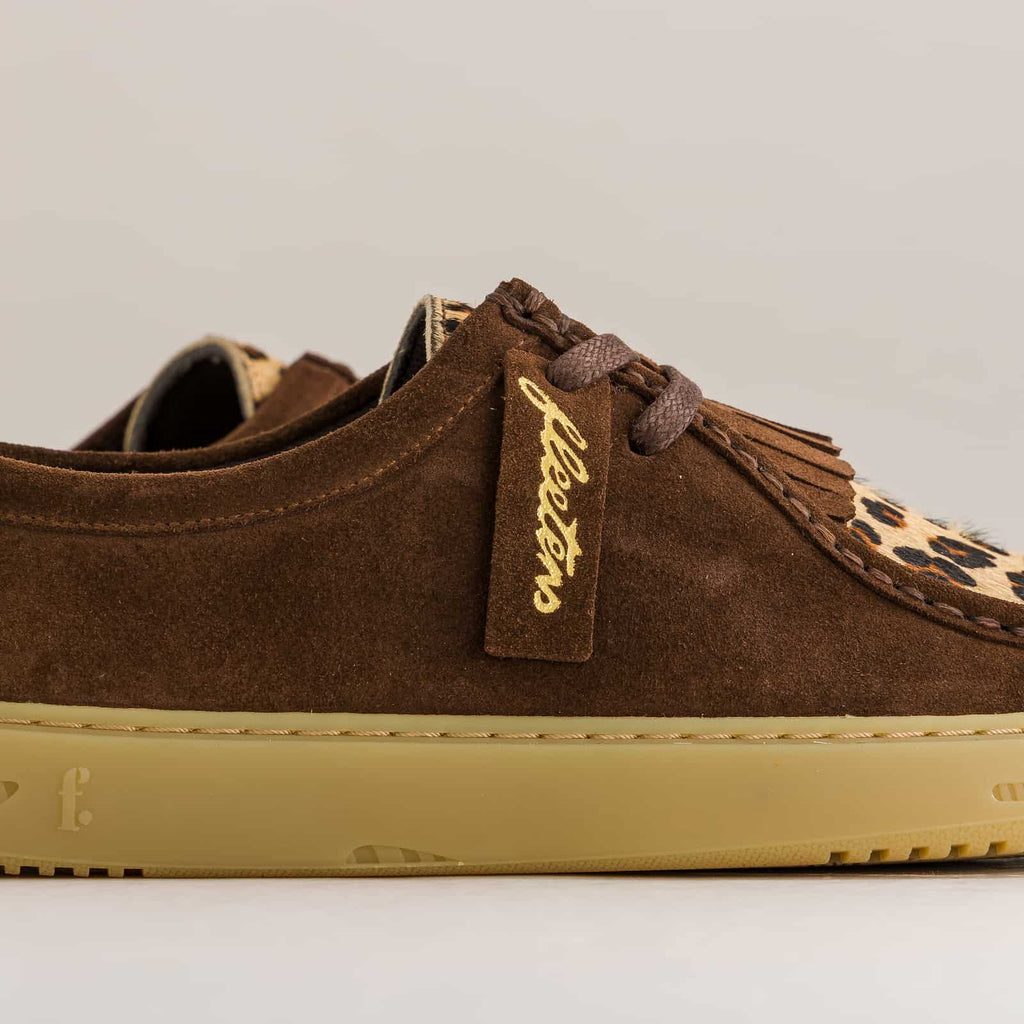 Brown suede sneaker with leopard print accents on a light gray background