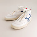 White mid-ankle barefoot sneakers with blue accents on a light gray background