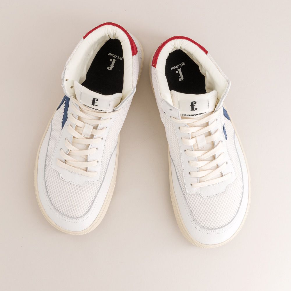 White sneakers with red and blue accents on a light beige background