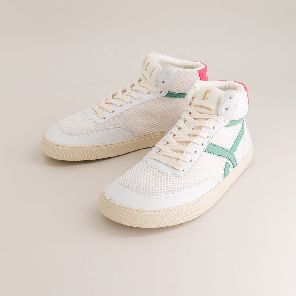 White mid-ankle barefoot sneakers with a green accent on a beige background