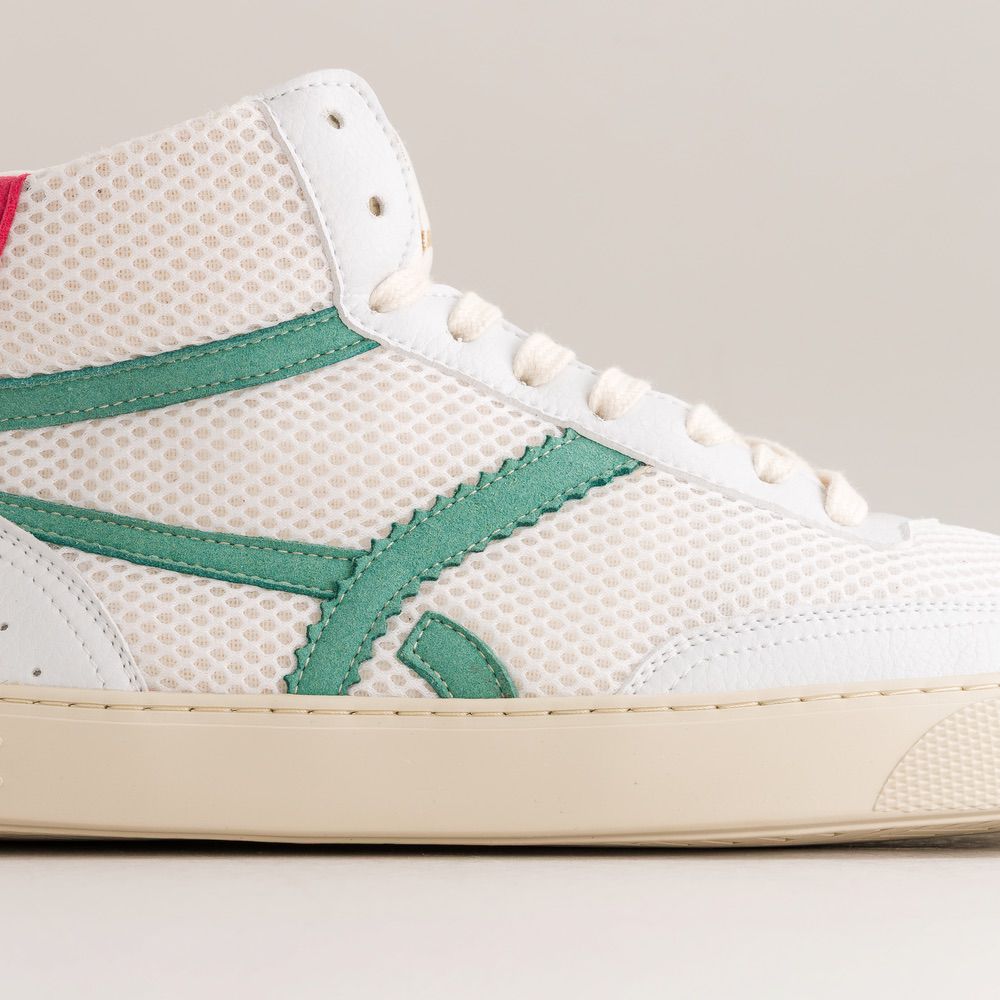 White mesh sneaker with green accents on a neutral background
