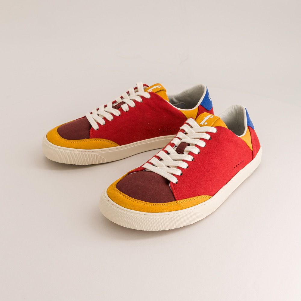 Colorful barefoot sneakers with red, yellow, and brown accents on a light gray background