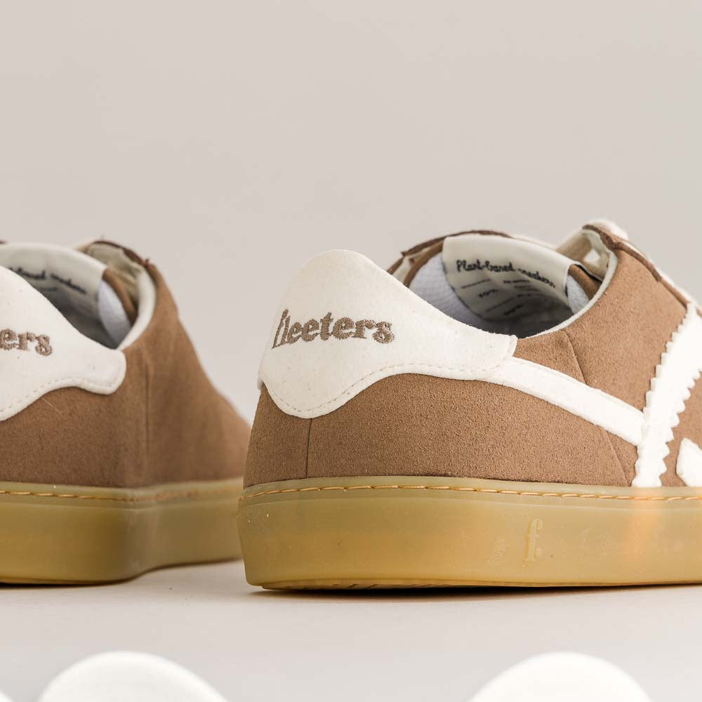 Brown sneakers with white soles on a light gray background