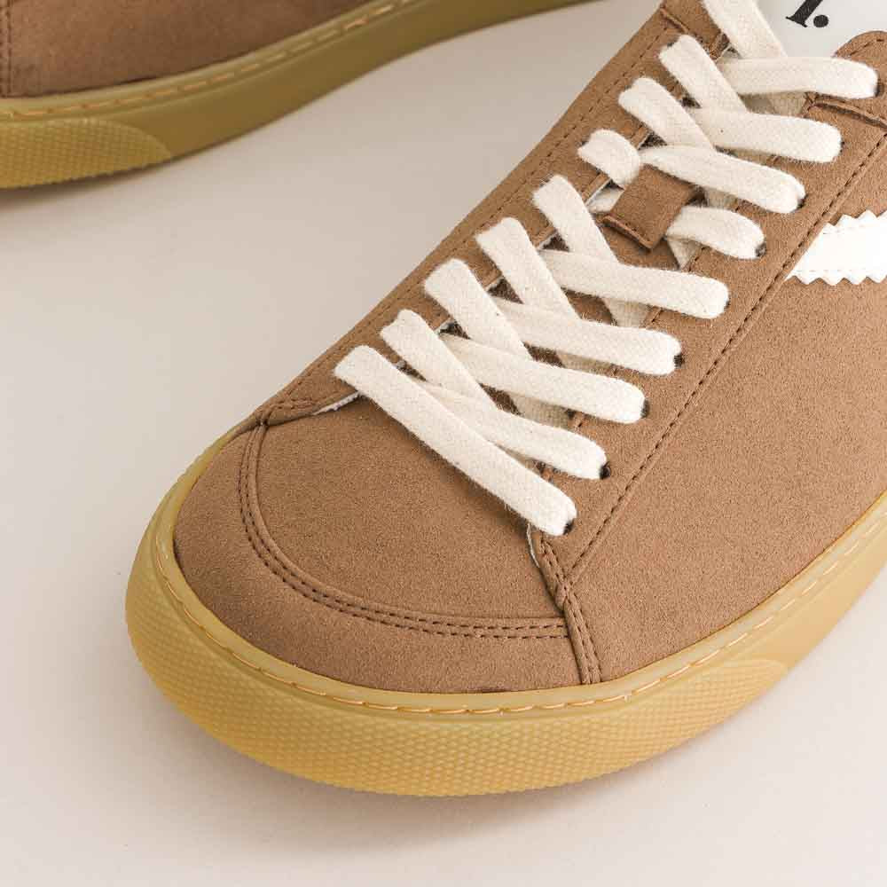 Brown  barefoot sneaker with white laces on a light background