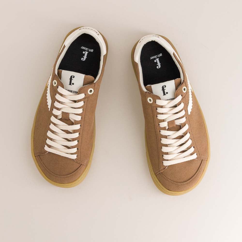 Pair of brown  barefoot sneakers with white laces on a light background