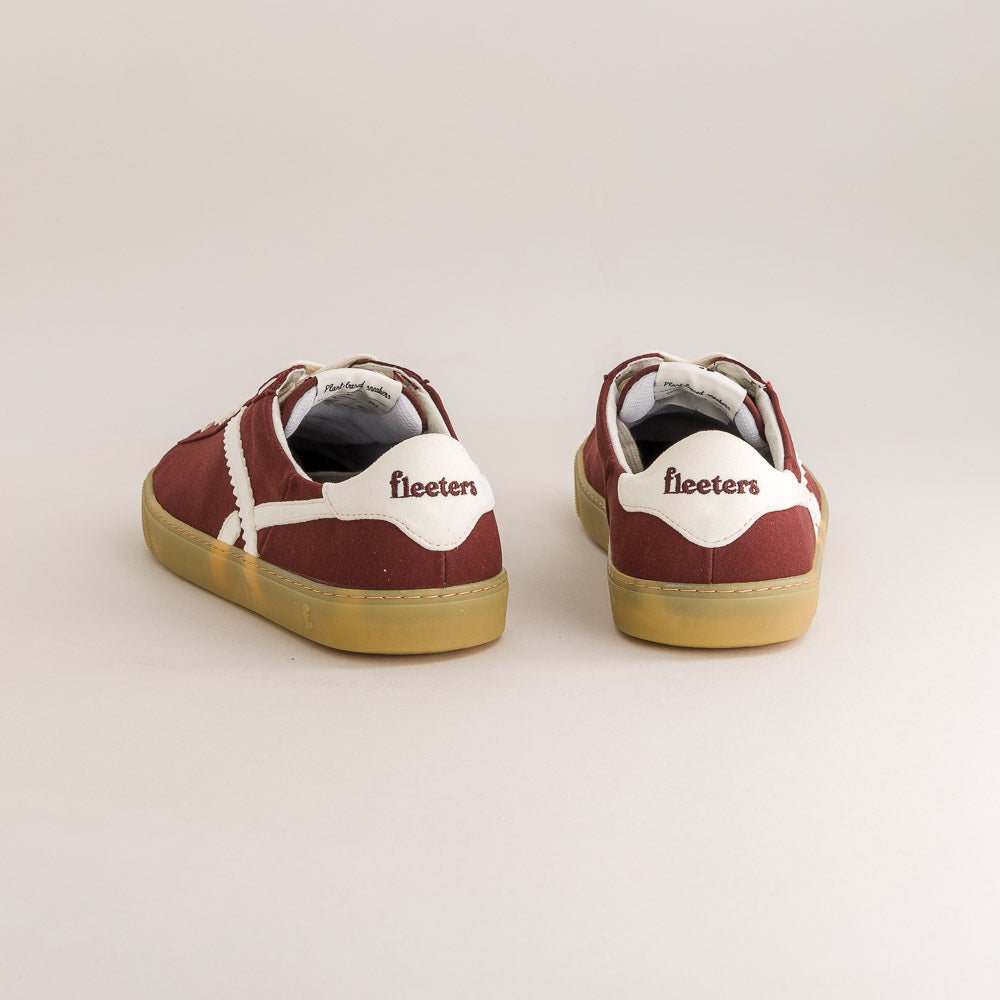 Pair of maroon sneakers with white soles on a light gray background