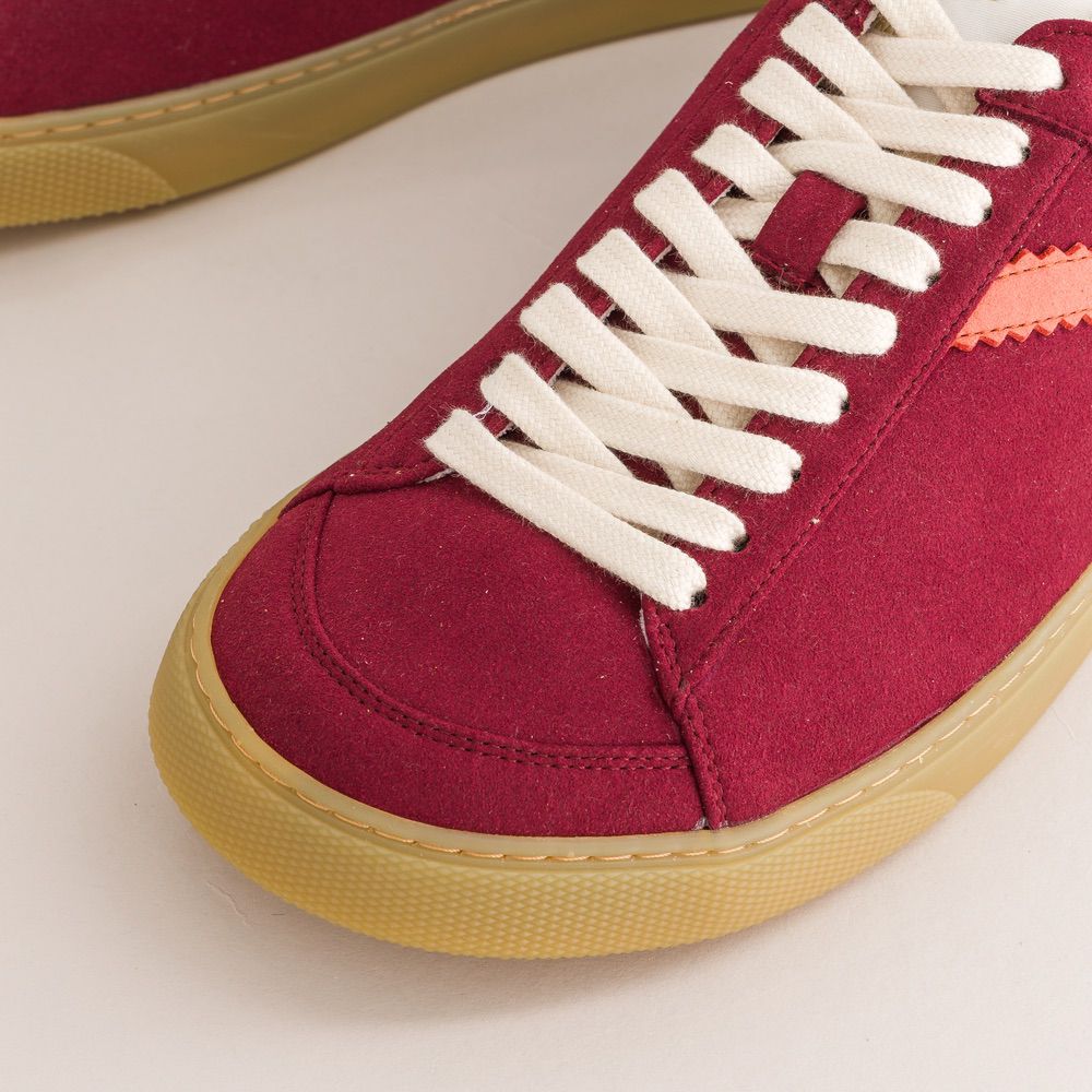 Red barefoot sneaker with white laces on a light background
