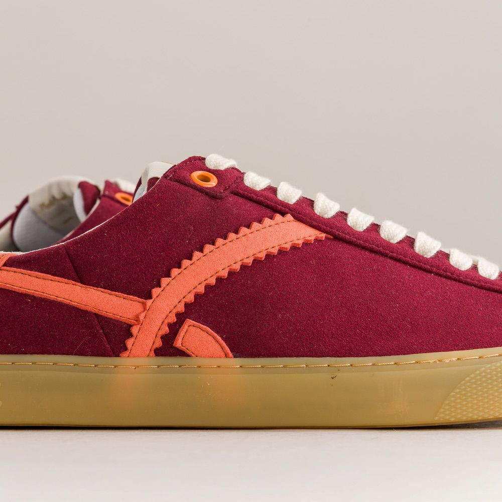 Red barefoot sneaker with orange accents on a gray background