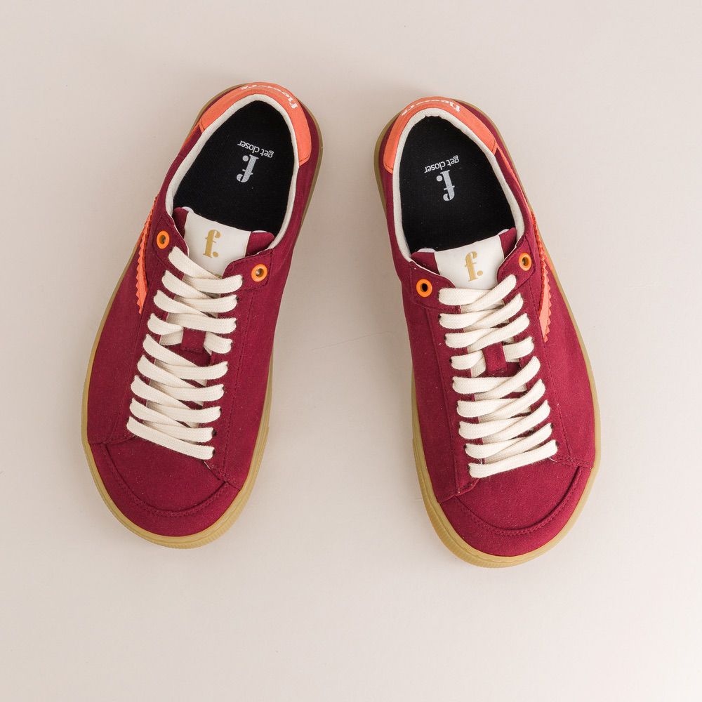 Red barefoot sneakers with white laces on a light gray background