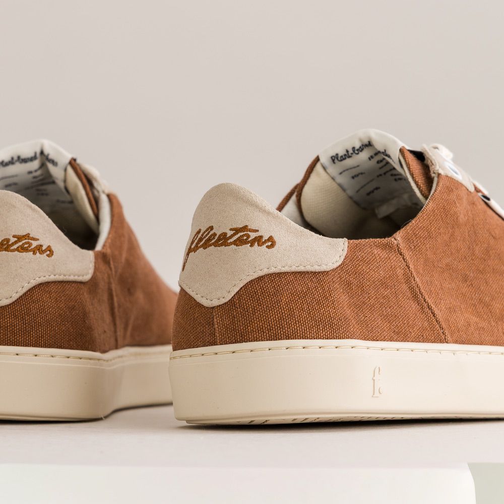 Brown minimalist sneakers with white soles and visible brand name on a light background