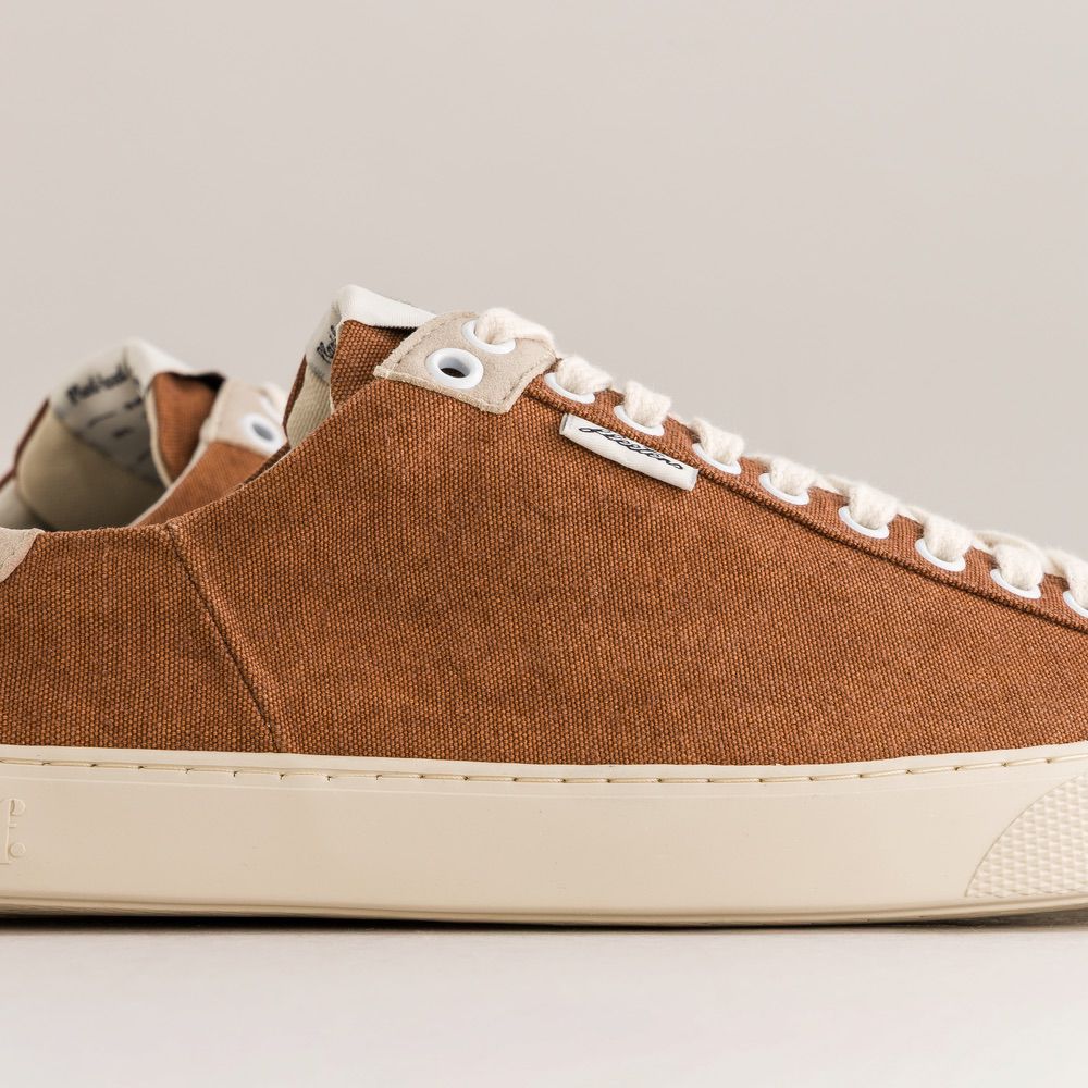 Brown minimalist sneaker with white laces on a light gray background
