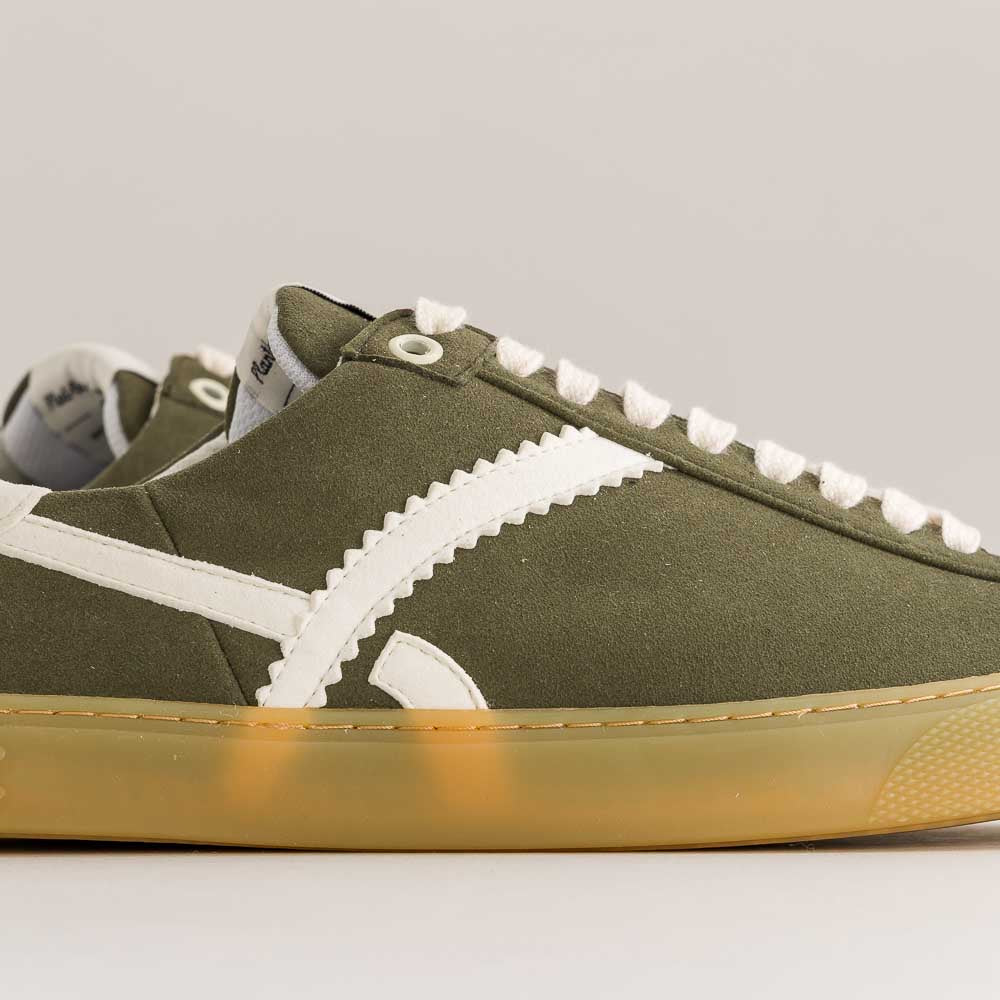 Green barefoot sneaker with white accents on a gray background