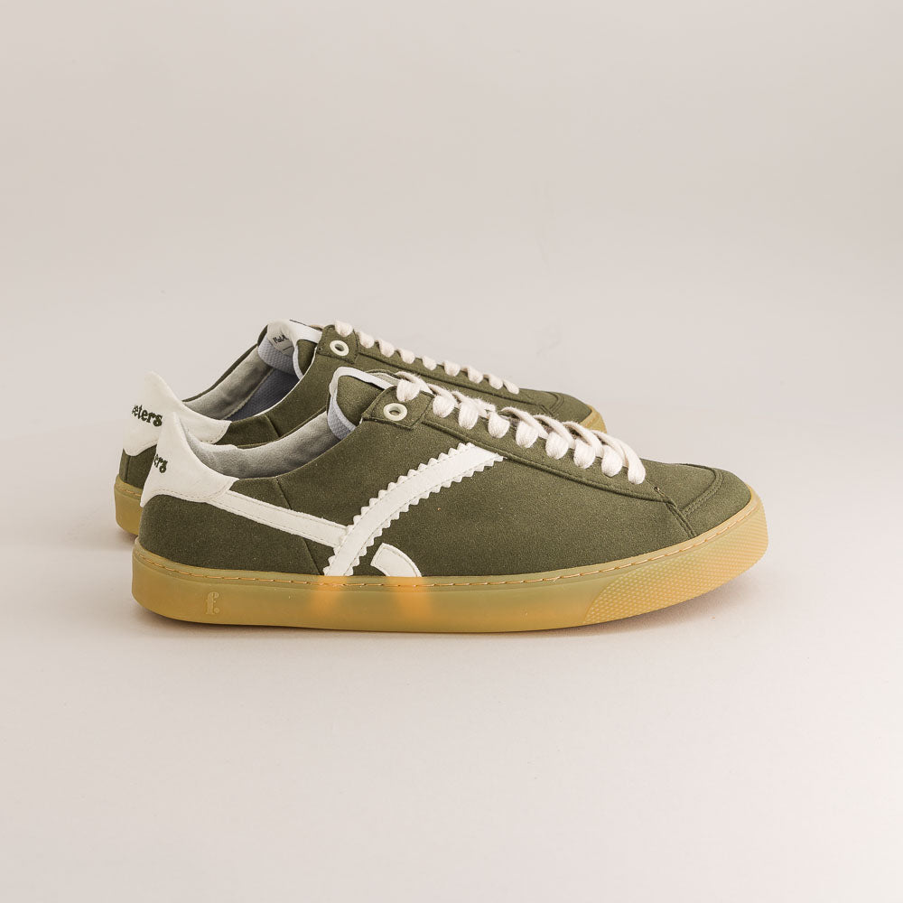 Green barefoot sneakers with white laces on a light gray background